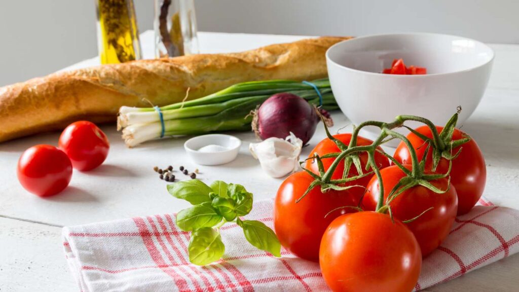 Frische Zutaten für Bruschetta mit Tomaten – reife Tomaten, knuspriges Brot, Knoblauch, Basilikum und Olivenöl.