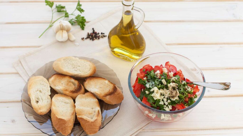 Zubereitung von Bruschetta mit Tomaten – knuspriges Brot, belegt mit marinierten Tomaten, Knoblauch und frischem Basilikum.