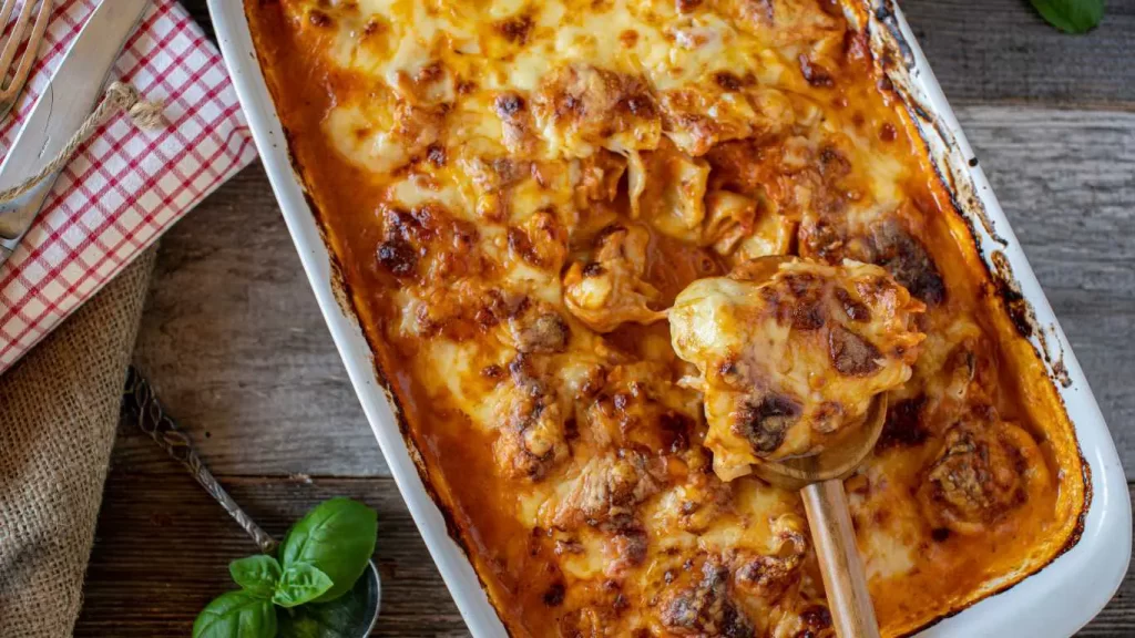 Einfache Tortellini-Auflauf vegetarisch, überbacken mit Käse, in Tomaten-Sahnesauce und frischem Gemüse serviert.