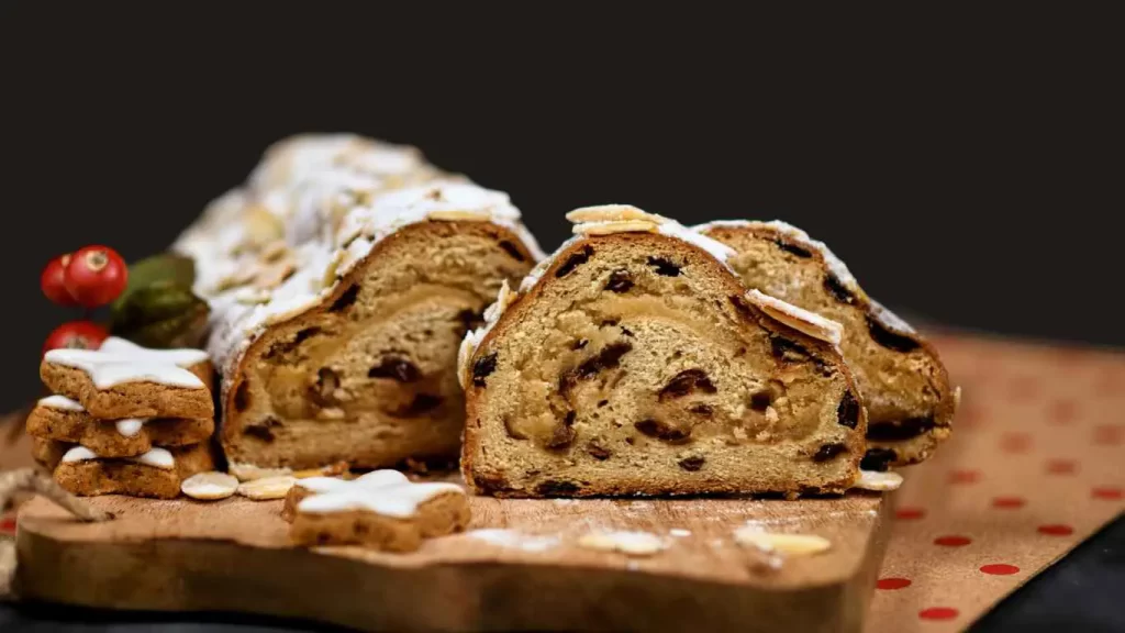  Omas traditioneller Christstollen mit Puderzucker auf einem Holztisch