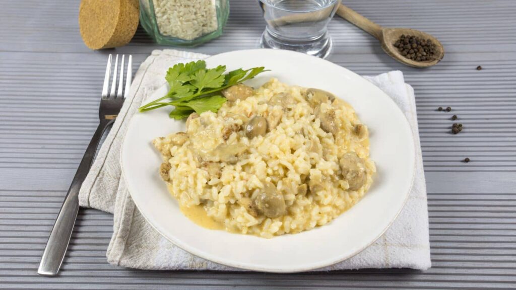 Pilzrisotto auf einem gedeckten Tisch serviert, mit frischen Pilzen und Parmesan – köstliches, cremiges Risotto