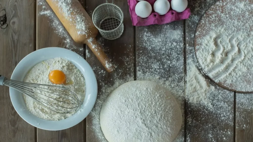 Zutaten für Plätzchenteig, darunter Mehl, Butter, Eier, Zucker und Vanille, auf einer Arbeitsfläche vorbereitet – Schritt-für-Schritt Anleitung für den perfekten Plätzchenteig.