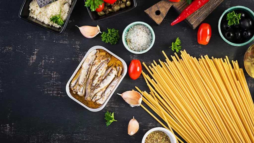 Zutaten für Spaghetti alla Puttanesca: Spaghetti, Tomaten, Oliven, Kapern, Knoblauch, Chilischoten und Sardellen.