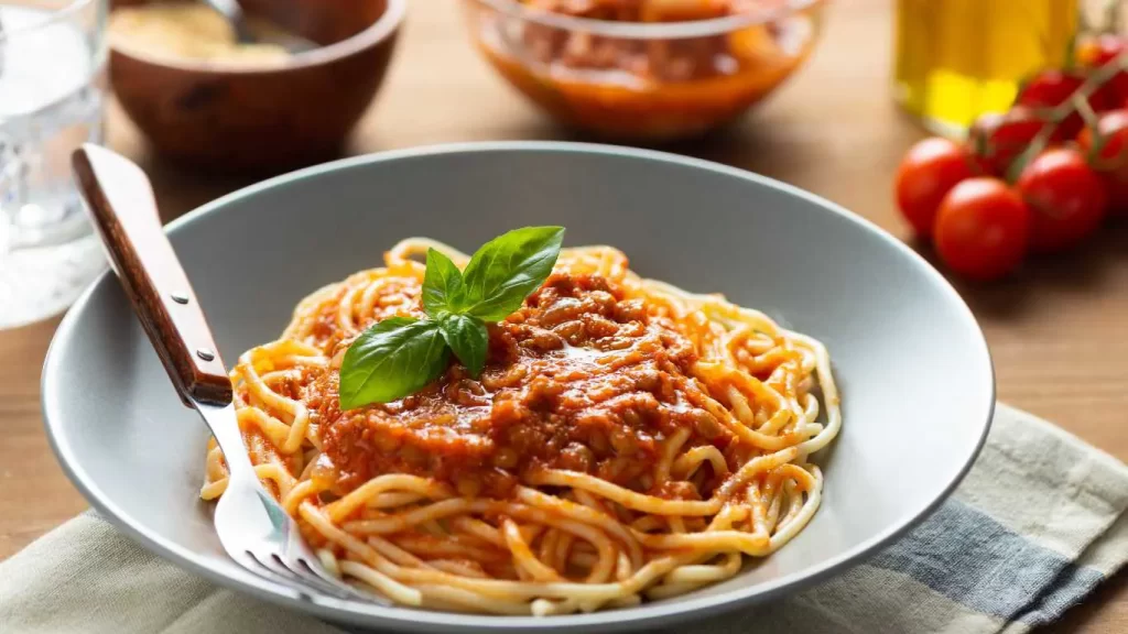 Servierte vegetarische Bolognese mit Linsen, angerichtet mit Spaghetti und frischem Basilikum – leckere, fleischlose Option.