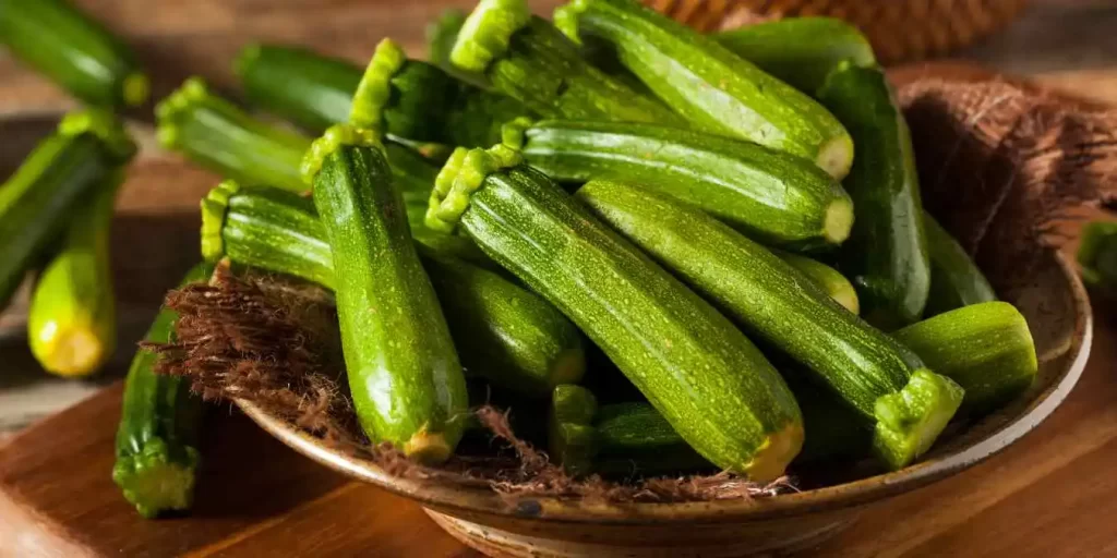 Ganzes Zucchini auf einem Teller zur Vorbereitung eines frischen Zucchinisalats