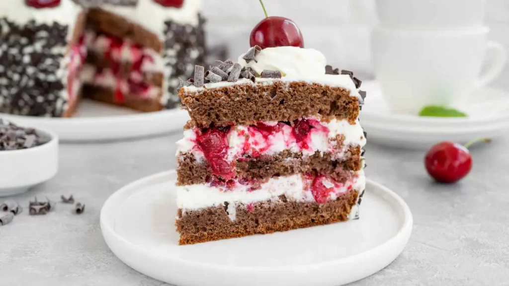 Ein Stück Schwarzwälder Kirschtorte mit Sahne, Schokoladenboden und Kirschen