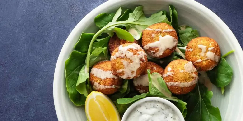 Knusprige Falafel mit frischem Salat, Zitronenstücken und cremiger Tahini-Soße