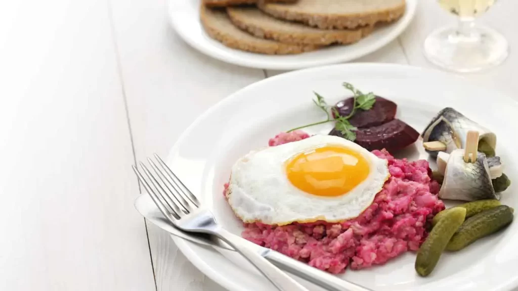 Labskaus mit Brot, serviert mit Rote Beete, Spiegelei und Matjes – norddeutsche Spezialität