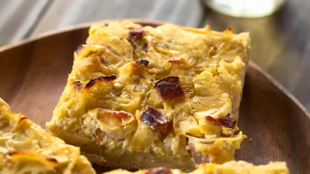 Leckeres Zwiebelkuchen Stück mit knuspriger Kruste und würziger Zwiebel-Speck-Füllung auf einem Teller