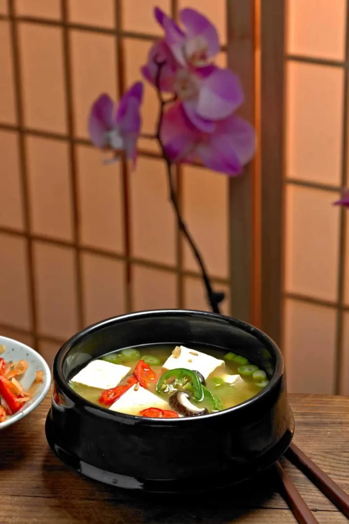 Servierte Miso Suppe in einer Schale mit Tofu, Seetang und Frühlingszwiebeln, typisch japanisch angerichtet.