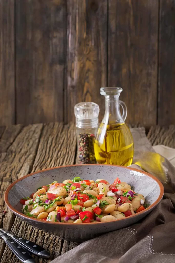 Gesunder Salat aus weißen Bohnen mit frischen Kräutern, Tomaten, Paprika und einem leichten Olivenöl-Dressing