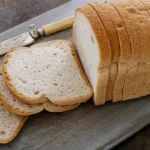 Frisch gebackenes glutenfreies Brot mit goldbrauner Kruste auf einem Holzbrett