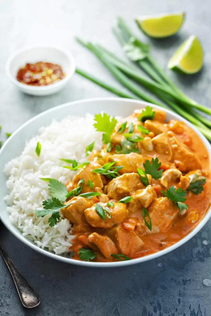 Hähnchen Curry mit Reis, serviert mit frischen Kräutern und einer Scheibe Zitrone – würziges Curry mit saftigem Hähnchen und duftendem Reis.