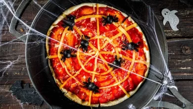 Halloween-Pizza mit gruseligen Belägen in Form von Spinnen und Gesichtern