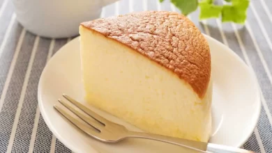 Käsekuchen ohne Boden auf einem weißen Teller, serviert mit einer leichten Puderzucker-Schicht
