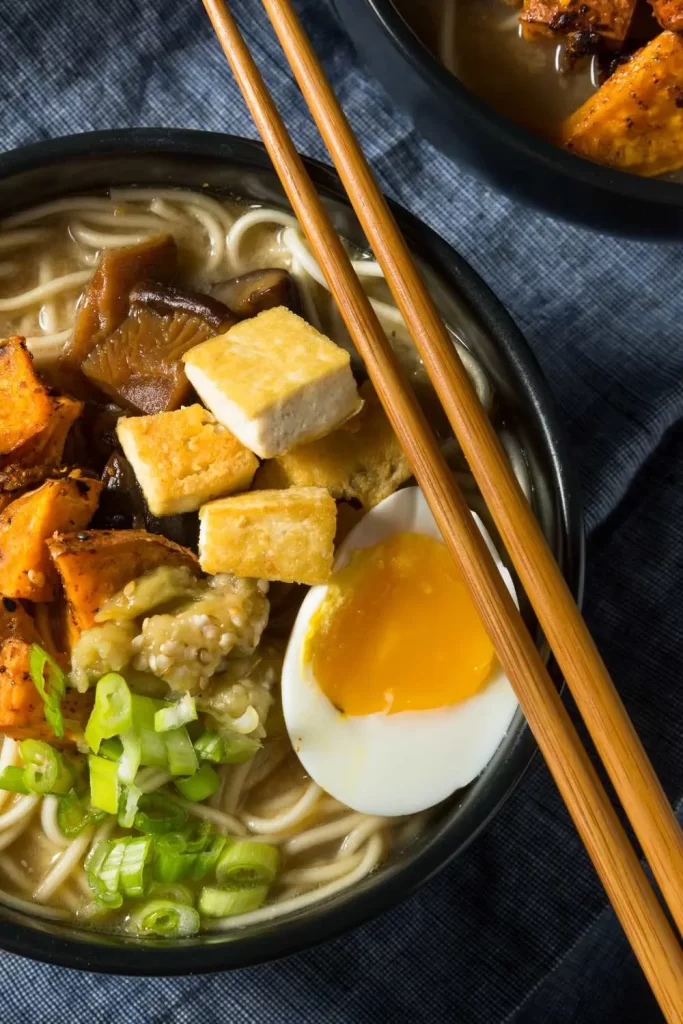 Schüssel mit leckerem vegetarischem Ramen, verfeinert mit frischem Gemüse, Nudeln und würziger Brühe