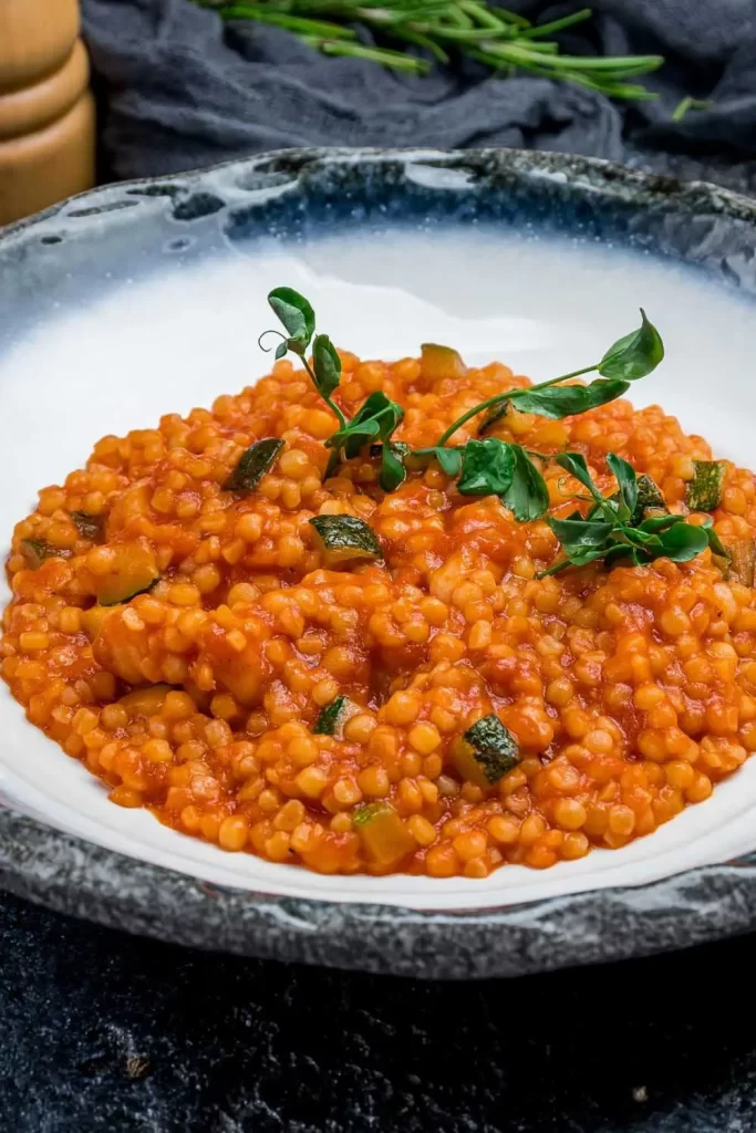 Traditionelle Fregola Sarda aus Sardinien, serviert mit Meeresfrüchten und mediterranen Kräutern