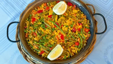 Vegetarische Paella mit Paprika, Zucchini, Tomaten und Safran-Reis in einer Pfanne