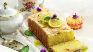Zitronen-Buttermilch-Kuchen auf einem Teller, garniert mit Zitronenscheiben und Glasur.