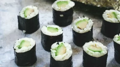 Frisches vegetarisches Sushi mit Avocado, Gurke und Karotten auf einem Bambusbrett serviert