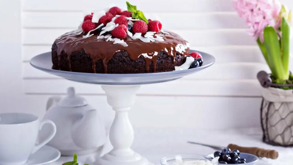 Laktosefreier veganer Schokokuchen mit dunkler Schokolade und frischen Beeren dekoriert