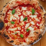 Frisch gebackene Neapolitanische Pizza mit knusprigem Rand, fruchtiger Tomatensoße und geschmolzenem Mozzarella