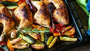 Traditionelles Hähnchen mit Ofengemüse auf einem Blech, knusprig gebacken und aromatisch gewürzt